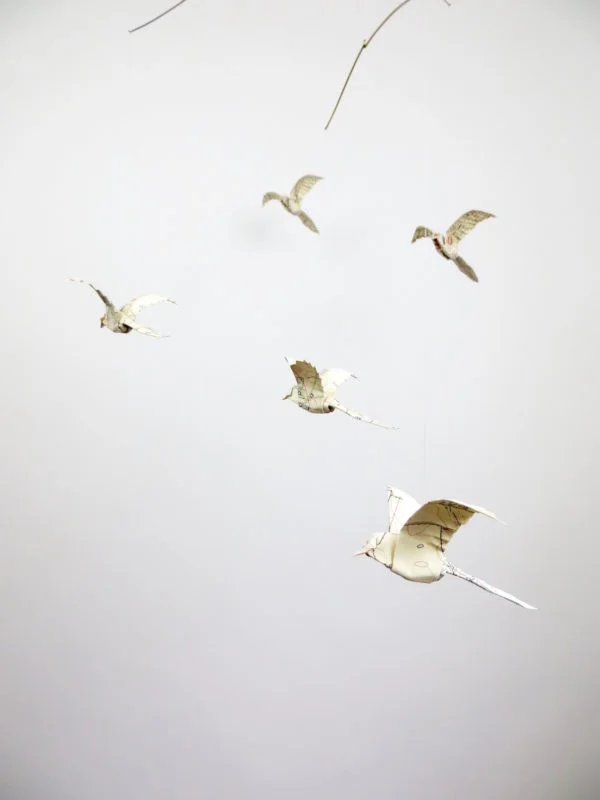 A hanging mobile with white origami birds