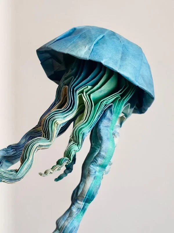 A close-up of a blue and green origami jellyfish