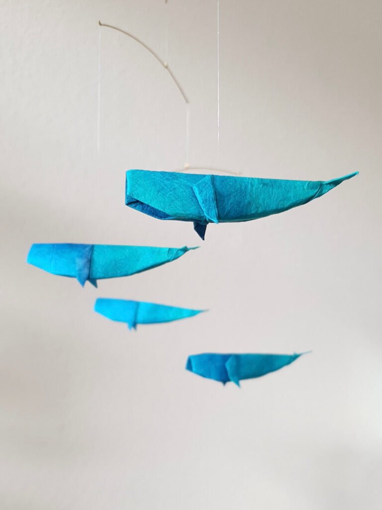 A hanging mobile with blue origami whales