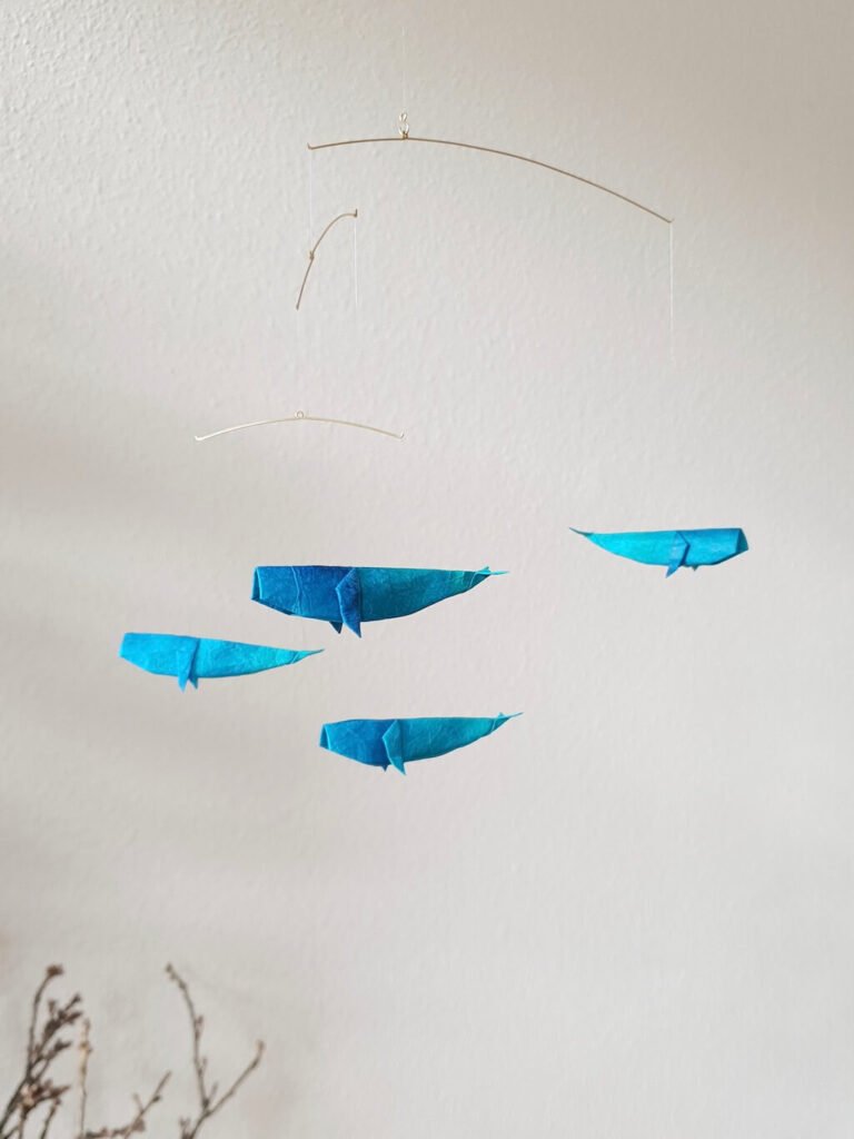 A hanging mobile with blue origami whales
