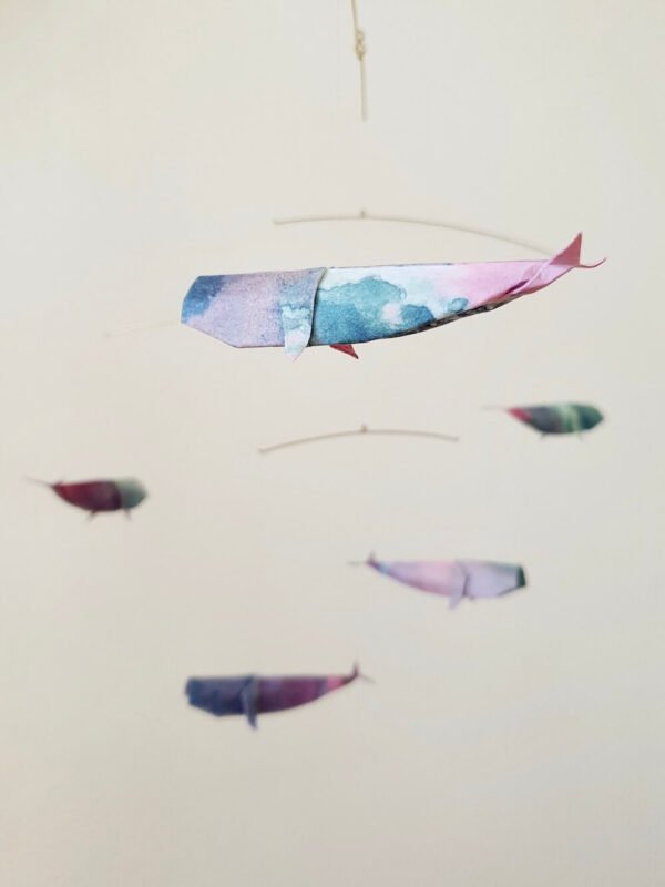 A hanging mobile with colorful origami whales