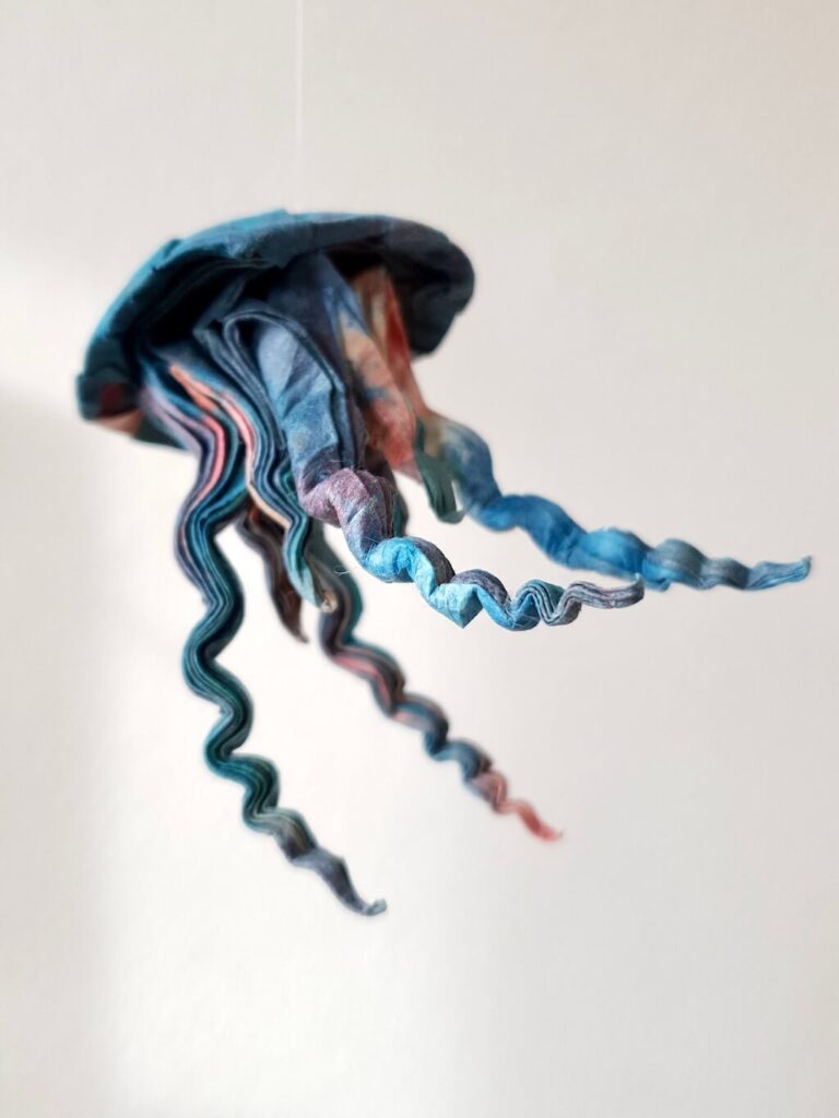 A blue and red origami jellyfish folded from Lokta paper