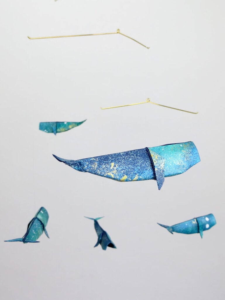 A hanging mobile with blue and golden whales