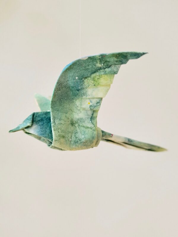 A blue and green origami bird folded from kozo washi