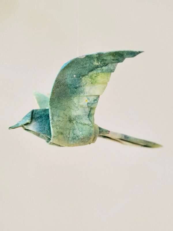 A blue and green origami bird folded from kozo washi