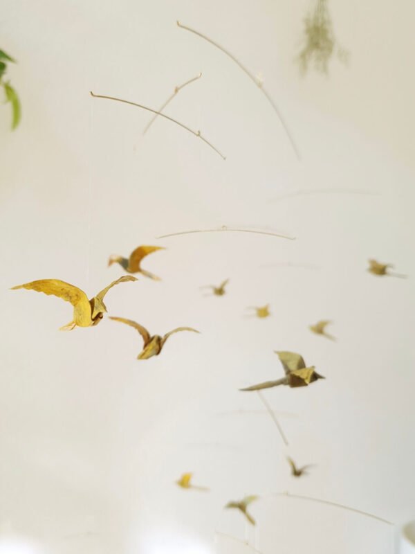 A hanging mobile with many small origami birds in yellow and brown colors