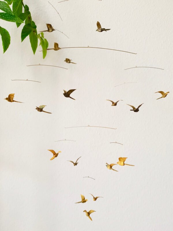 A hanging mobile with many small origami birds in yellow and brown colors