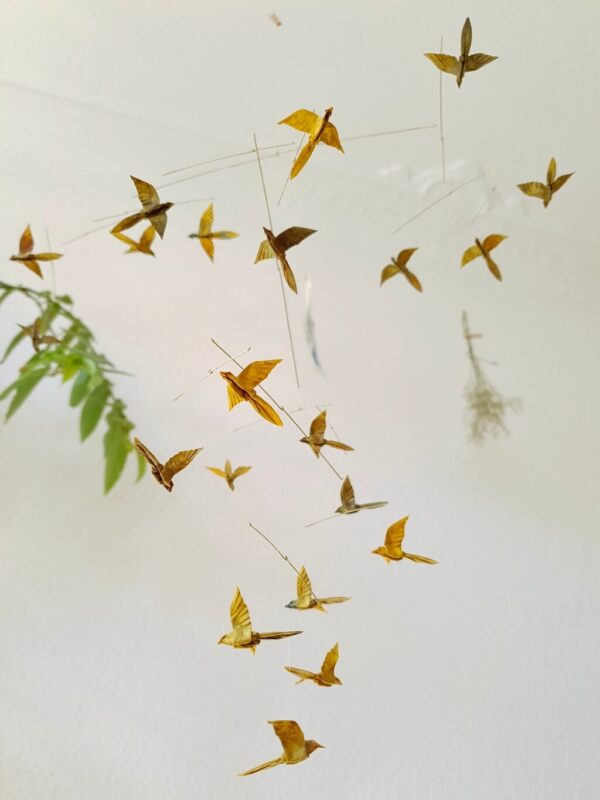 A hanging mobile with many small origami birds in yellow and brown colors