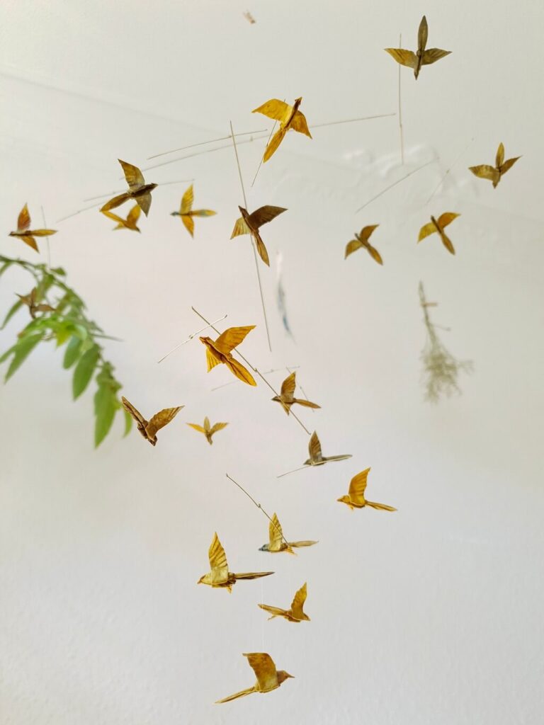 A hanging mobile with many small origami birds in yellow and brown colors