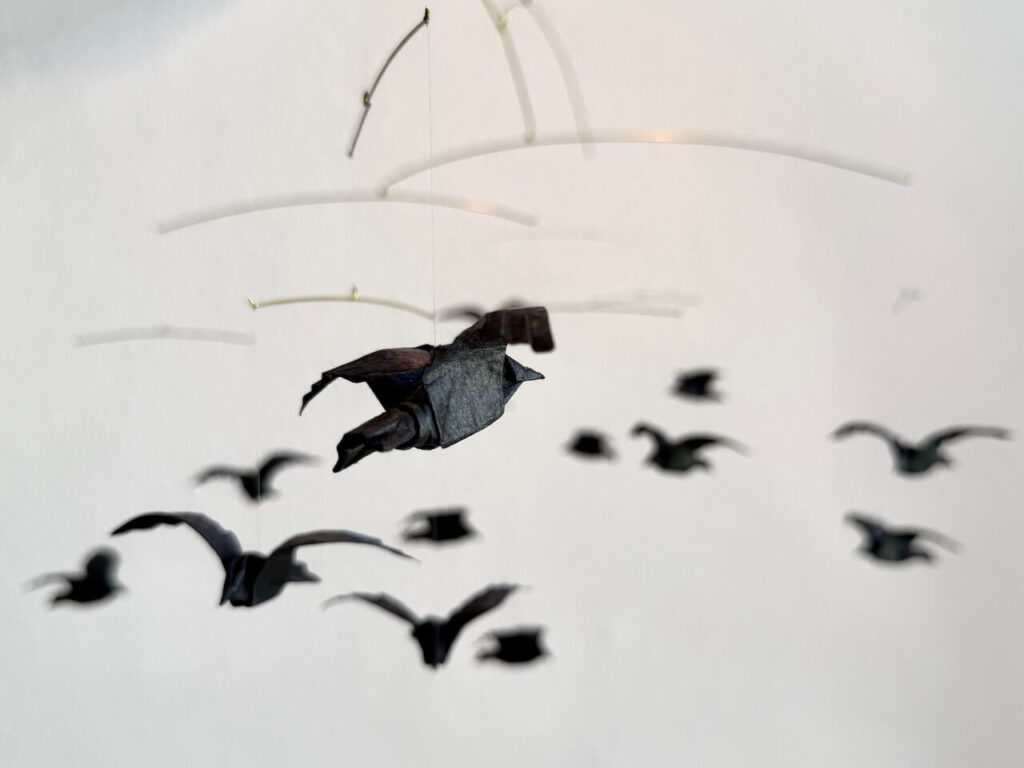 A large hanging mobile with 13 origami crows