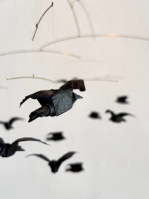 A large hanging mobile with 13 origami crows