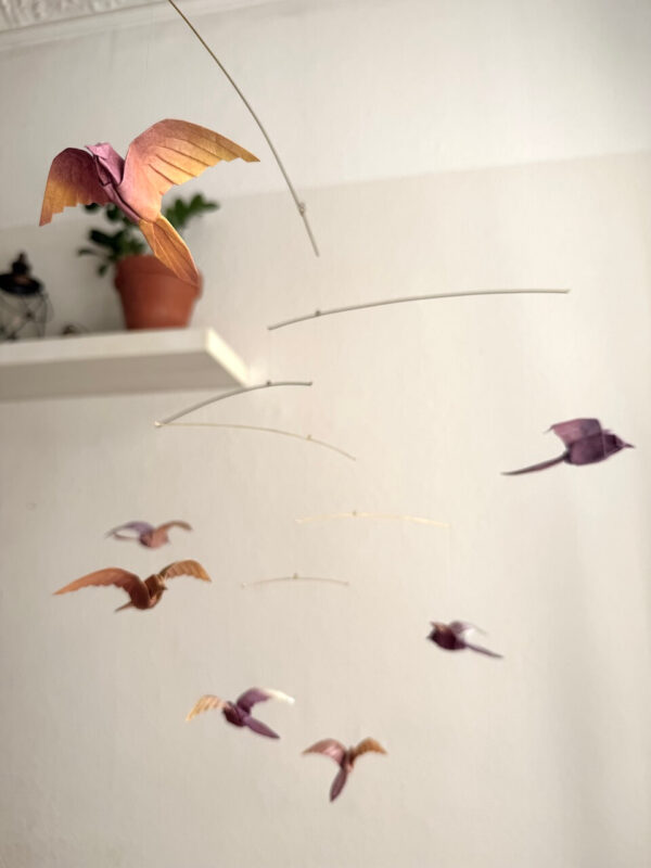 A hanging mobile with 7 origami birds in sunset colors