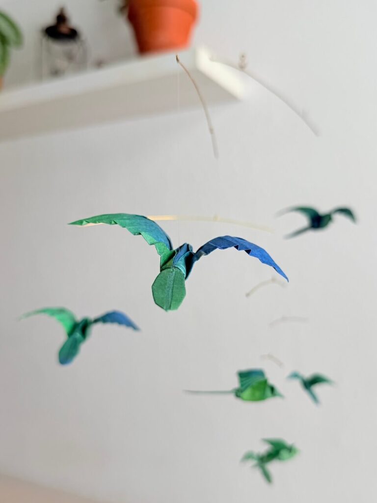 A hanging mobile with 7 green origami birds