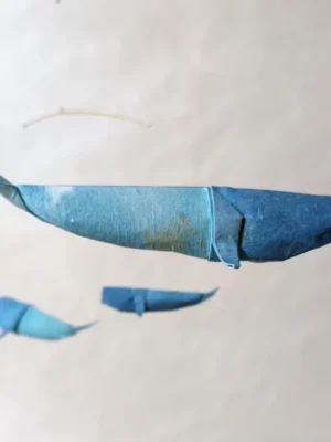A hanging mobile with 3 blue kirigami whales