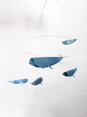 A hanging mobile with 5 blue kirigami whales